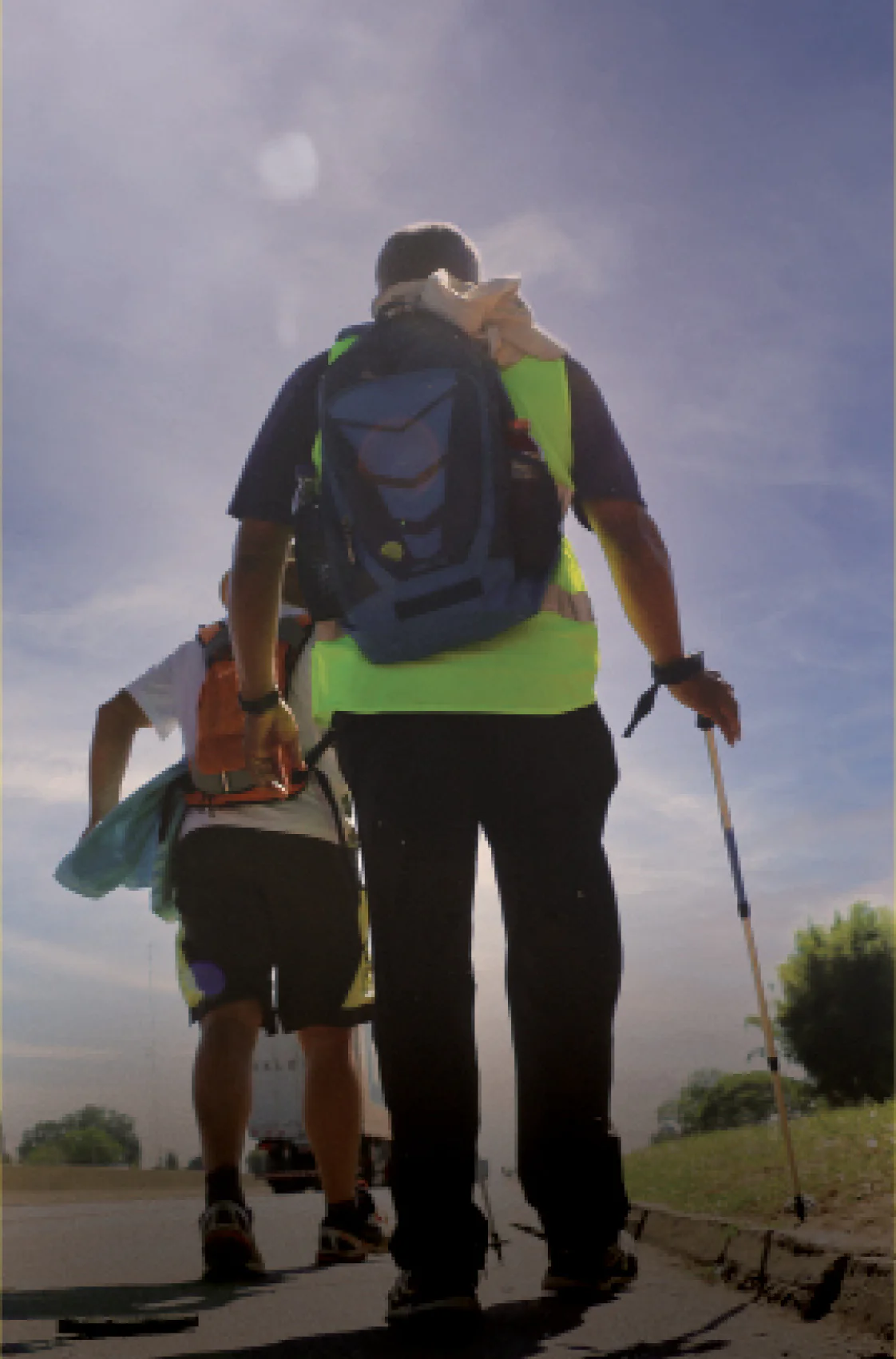 Homem e mulher com mochilas, caminhando juntos em um ambiente ao ar livre.